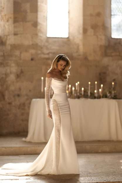 Envy Eva Lendel. Satin, lace and beaded off shoulder fitted wedding dress with long sleeves. Chameleon Bride Bournemouth Dorset