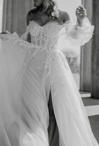 Brannah D3787 Essense of Australia wedding dress. Boned corset detailing on bodice with detachable off shoulder balloon sleeves. Floaty flowy aline dress with leg split. Chameleon Bride Dorset